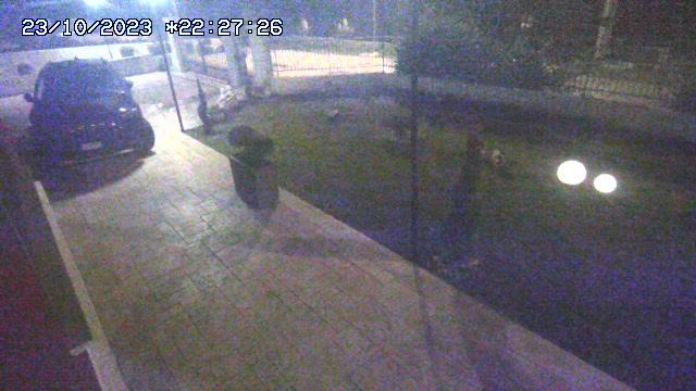 A webcam image of a man walking in the rain