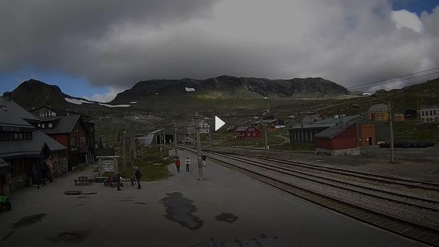 A picture of a train station with a mountain in the background
