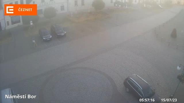 Размытое изображение улицы с автомобилями, припаркованными на обочине.