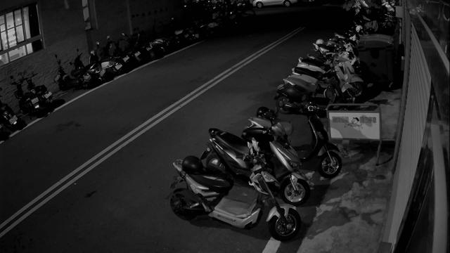 A black and white photo of motorcycles parked on the side of the road
