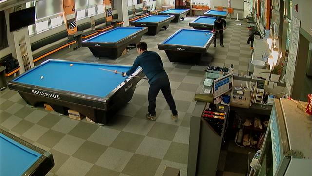 A group of people playing a game of pool