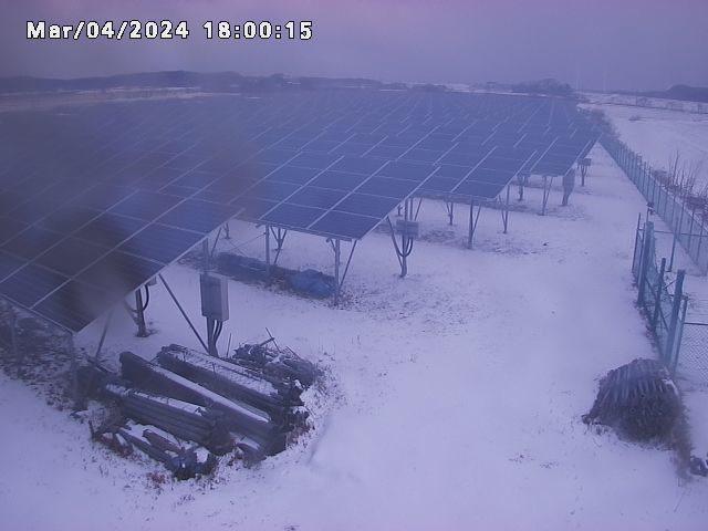 A picture of a solar farm with clouds in the background